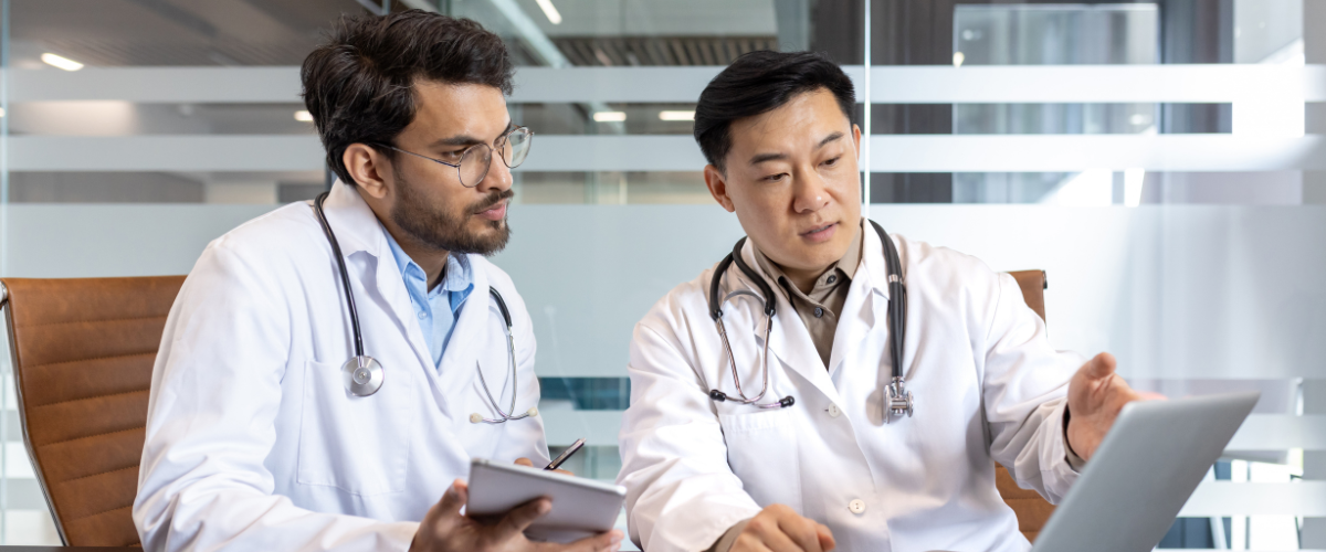 An older physician and younger physician sit down to discuss Group Health Insurance