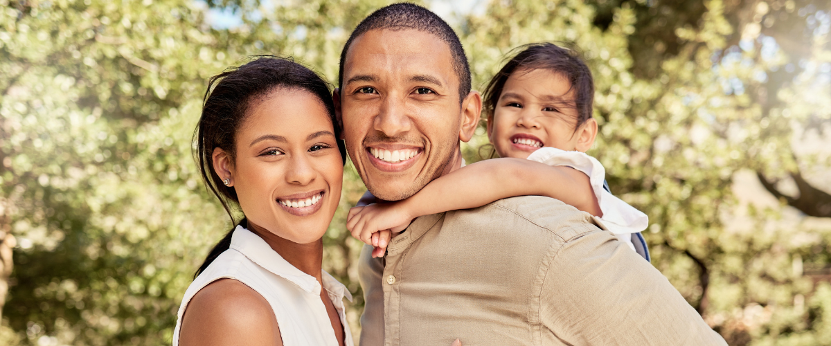 Mother, Father, and Daughter outside smiling at the camera