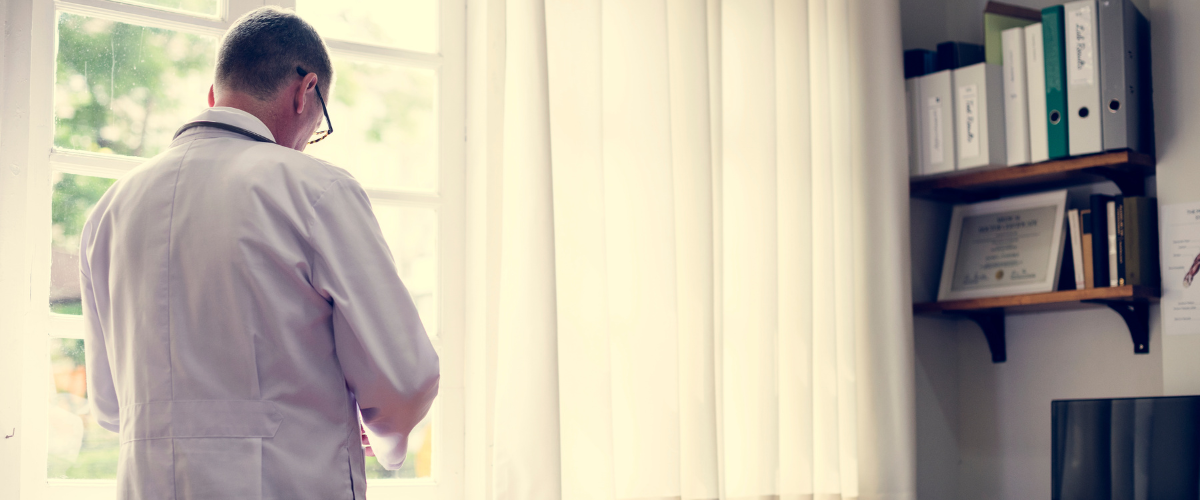 Doctor with his back turned looking down at his phone