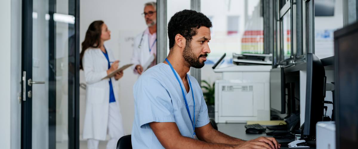 Young male physician working on a computer at a desk