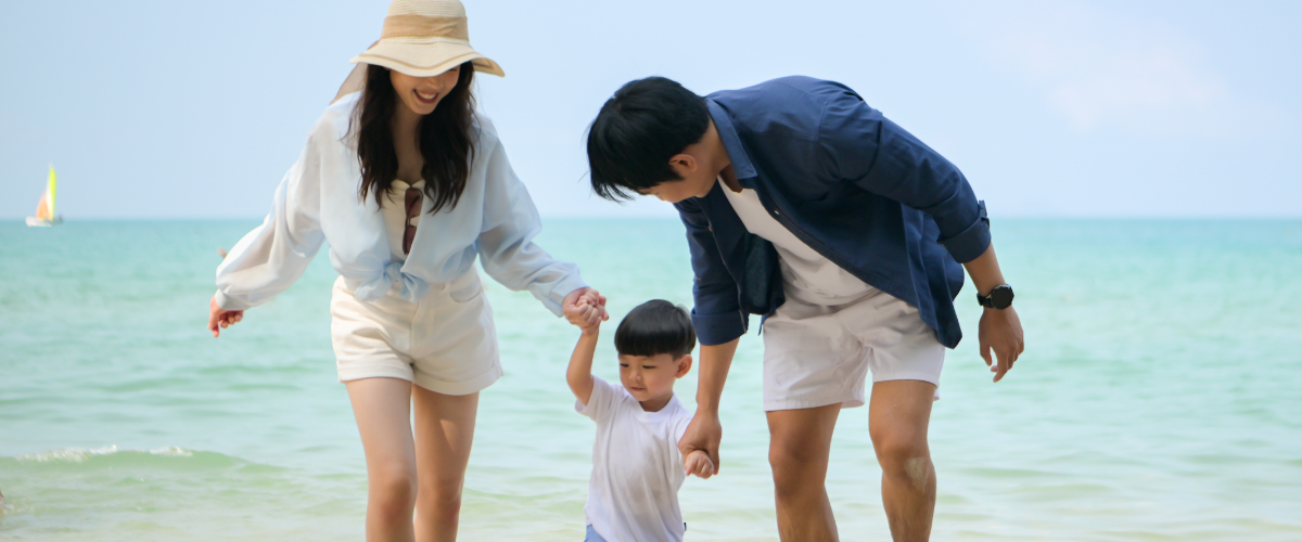 Family with young child happily playing in the water on a warm beach